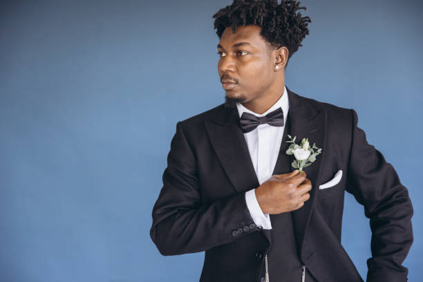 istock Elegant groom adjusting boutonniere on blue background 2191408711