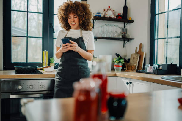 istock Woman wearing apron using smartphone in kitchen 2191409448