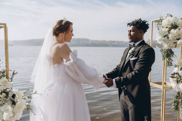 istock Interracial couple holding hands during wedding ceremony by the lake 2191409787