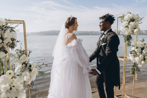 istock Interracial couple holding hands during wedding ceremony by the lake 2191409789