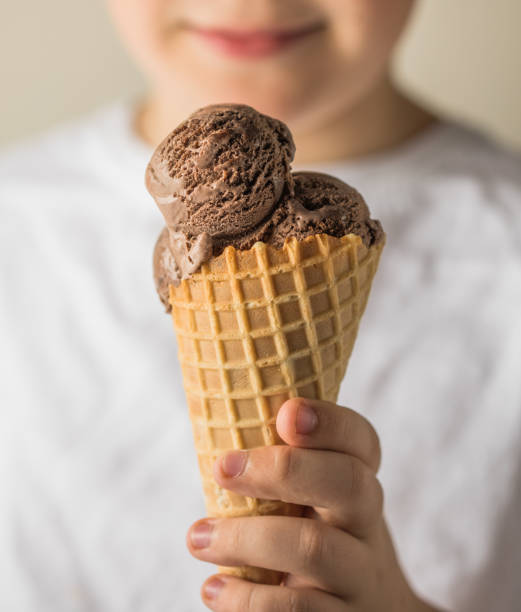 istock a human hand holds a ice cream cone up. nine year boy eating ice cream on white 2191410099