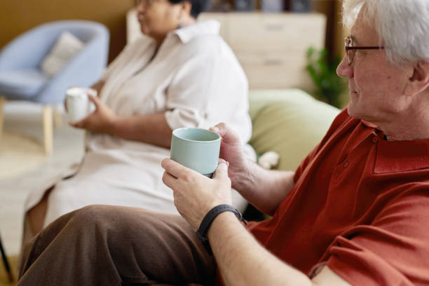 istock Senior Man Holding Mug with Friends at Home 2191411101