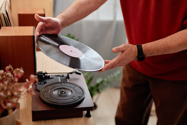 istock Senior Man Setting Vinyl Record on Retro Record Player at Home 2191411114