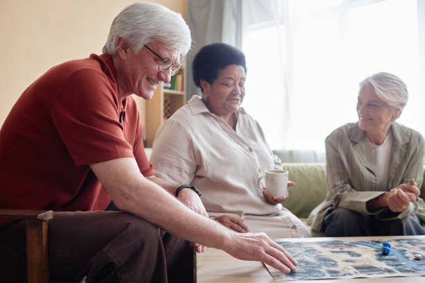 istock Smiling Senior Man Playing Board Game with Friends 2191411142