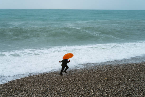 Lonely man walking on the beach on a rainy day