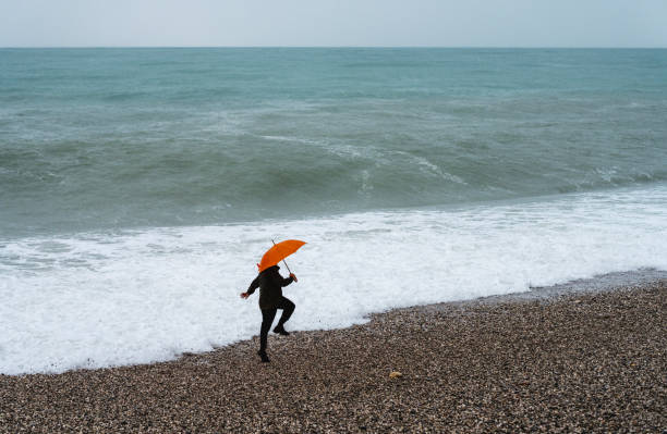 Lonely man walking on the beach on a rainy day