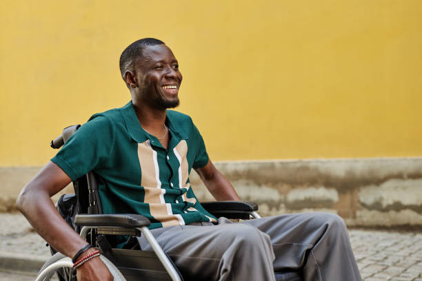 istock Black Man with Disability using Wheelchair Against Bright Yellow Wall 2191411460