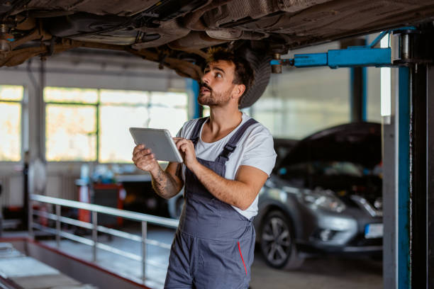 istock Auto Mechanic Inspecting Car's Undercarriage with Digital Tablet 2191413911