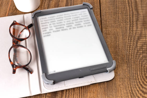 istock e-book reader and glasses on a wooden table. 2191414288