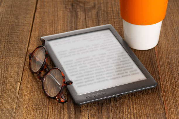 istock e-book reader and glasses on a wooden table. 2191414292