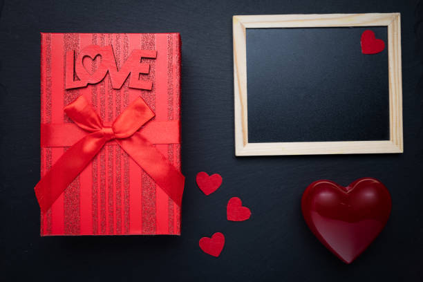 istock Photo frame and box with a gift on a black background. Space for text. Word LOVE. Congratulations on Valentine's Day. 2191414671