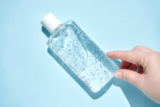 istock Caucasian female hand touching clear gel bottle on blue background with bubbles highlighting hygiene and skincare 2191424019