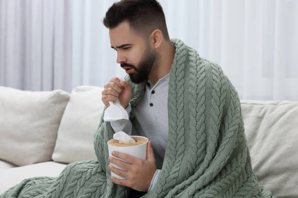 istock Sick man with tissue coughing at home 2191427895