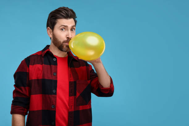 istock Man inflating yellow balloon on light blue background. Space for text 2191427918