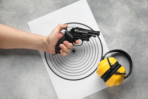istock Man with handgun, shooting target and bullets at gray table, top view 2191428657