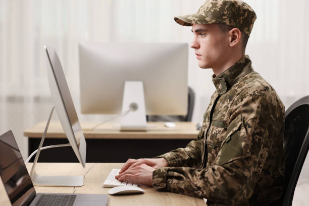 istock Military service. Young soldier working with computer at wooden table in office 2191428663