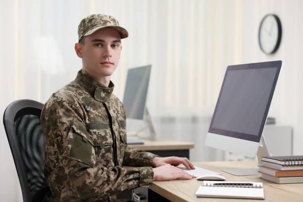 istock Military service. Young soldier working with computer at wooden table in office 2191428691