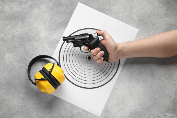 istock Man with handgun, shooting target and bullets at gray table, top view 2191428697
