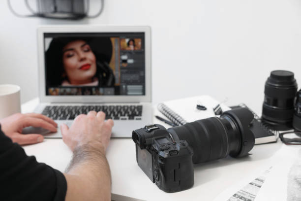 istock Professional photographer using laptop at table with digital camera, closeup 2191429231