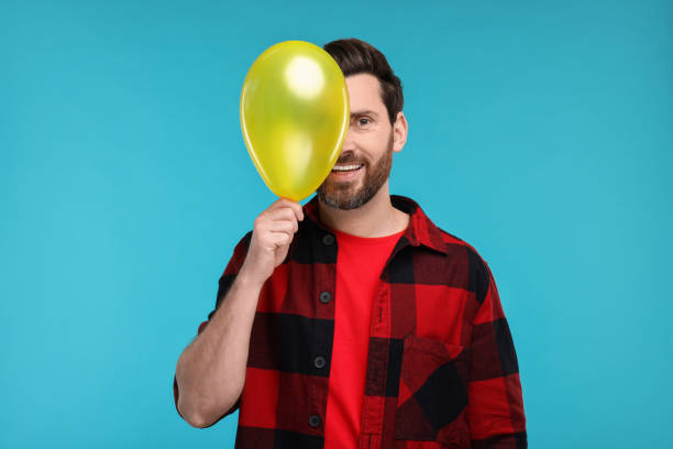 istock Happy man with yellow balloon on light blue background 2191429426