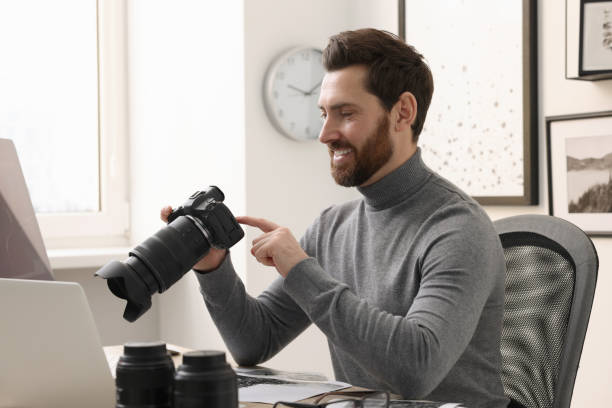 istock Professional photographer with digital camera at table in office 2191429473