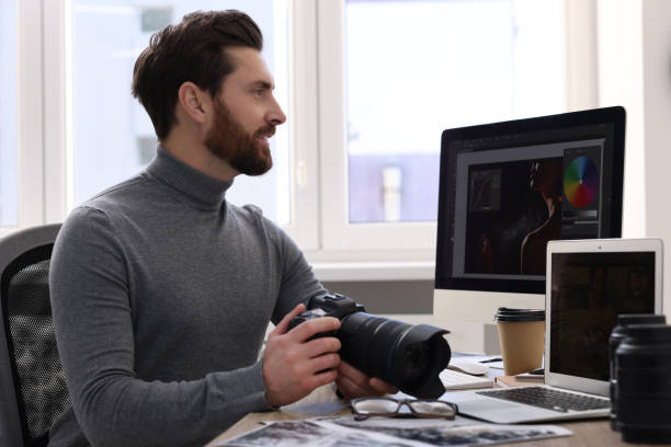 istock Professional photographer with digital camera at table in office 2191429477