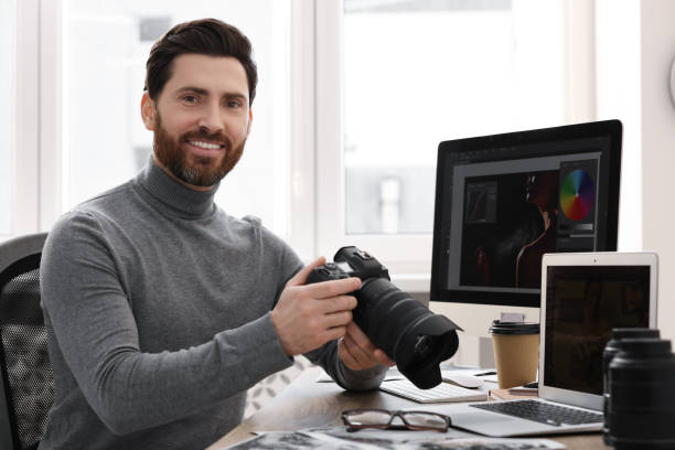 istock Professional photographer with digital camera at table in office 2191429489