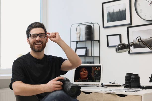 istock Professional photographer in glasses holding digital camera at table in office 2191429595