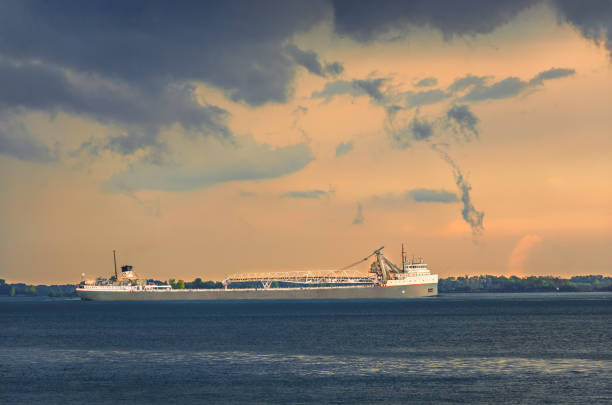 Beautiful  ocean sunset, with colourful clouds, dark waves and silhouette of a ship - oil tanker on the horizon with smoke coming from the ships exhaust pipe.