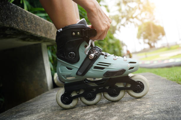 A woman is sitting on a bench and putting on her roller skates