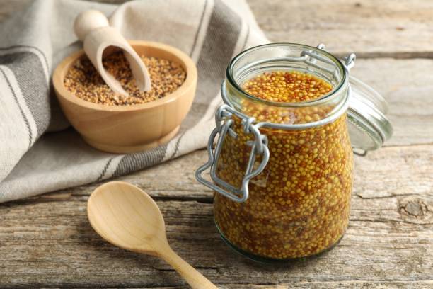 istock Whole grain mustard in jar and spoon on wooden table 2191432629