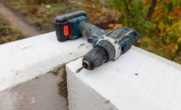 A blue and black power drill is sitting on a white wall
