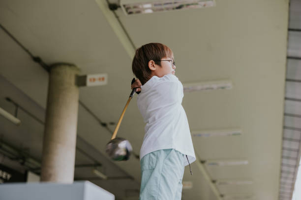 Thai boy is driving golf by himself after class.