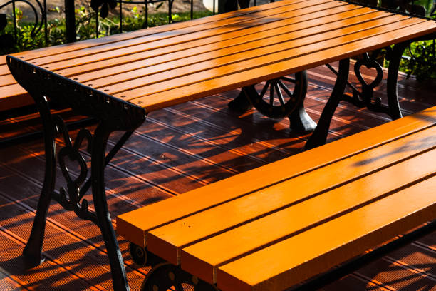 White patio set with a checkered tablecloth on a sunny wooden deck, overlooking a serene view.