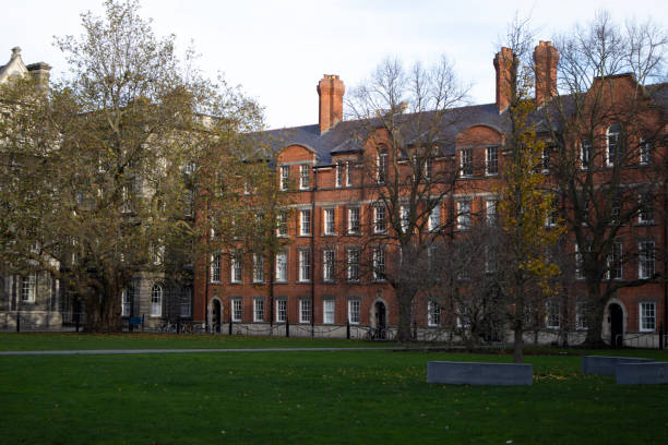 Beyond the park lawn is an old red brick building.        .