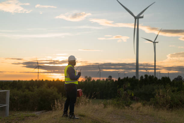 istock African american maintenance technician wearing a safety suit working overtime carrying toolbox walks into wind farm area to make urgent repairs at sunset. 2191443509