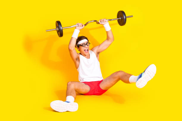 istock Enthusiastic young athlete lifting weights with joy against a vibrant yellow backdrop 2191444466