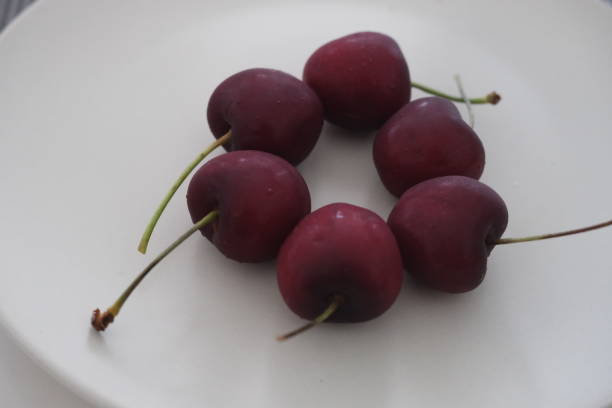 istock Fresh red cherries with stems arranged on a white plate 2191447916