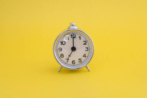 istock Analog alarm clock on yellow background. 7.00 am wake up time. 7:00 pm go to bed time. 2191448139