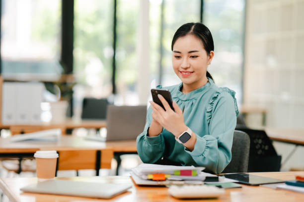 istock Cheerful beautiful Asian woman using smartphone to chat at her office 2191449494