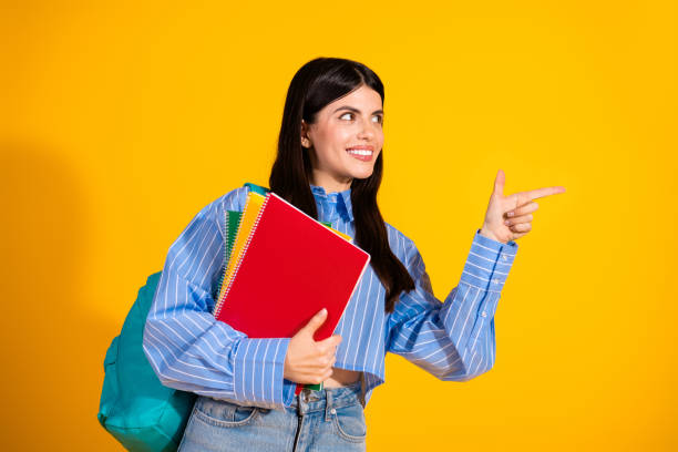 istock Young brunette student with notebooks pointing on yellow background 2191450992