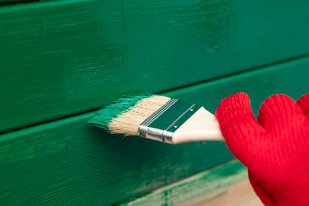 Man in protective glove carefully painting stitches of two planks