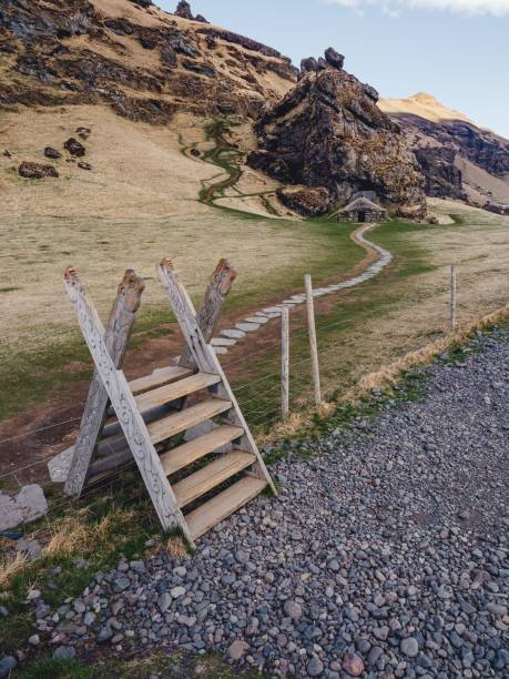 istock Rustic wooden stile over a fence on a rocky path leading to a hillside with a small cave dwelling. 2191455933