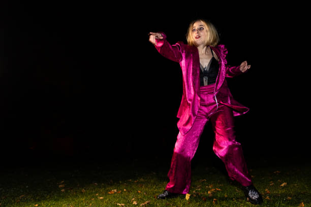 A woman in a pink suit is dancing in the dark. Scene is mysterious and intriguing