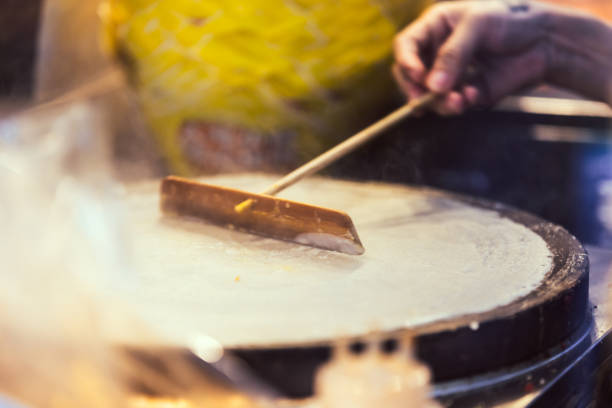 A woman is preparing crepe with egg at Chinatown street food market.