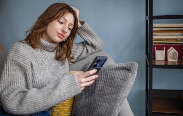 istock Woman on the couch checking phone after reading a book. 2191459316