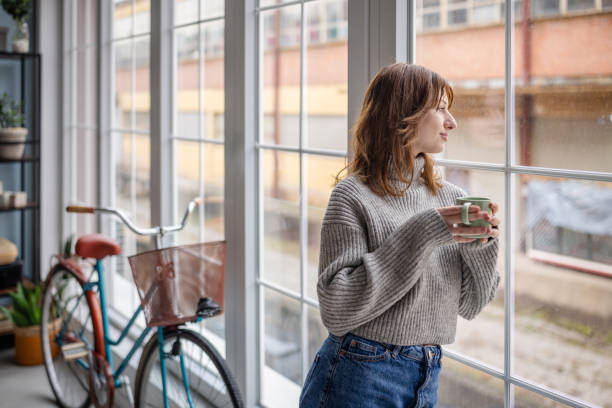 istock Woman holding mug near window in modern interior. 2191460045