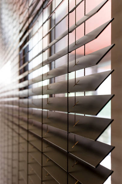 Wooden blinds on a window, close-up, side view. Horizontal blades of 50mm extend into the distance. This is clearly visible ladder and a hole in the blinds for the cord.