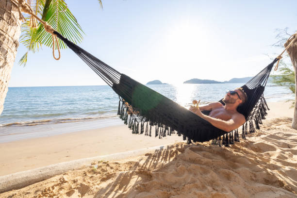 istock Man Relaxing in Hammock with Drink on Tropical Beach 2191461255