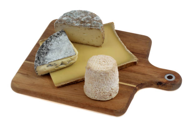 Assortment of French cheeses on a wooden cutting board top view closeup on white background